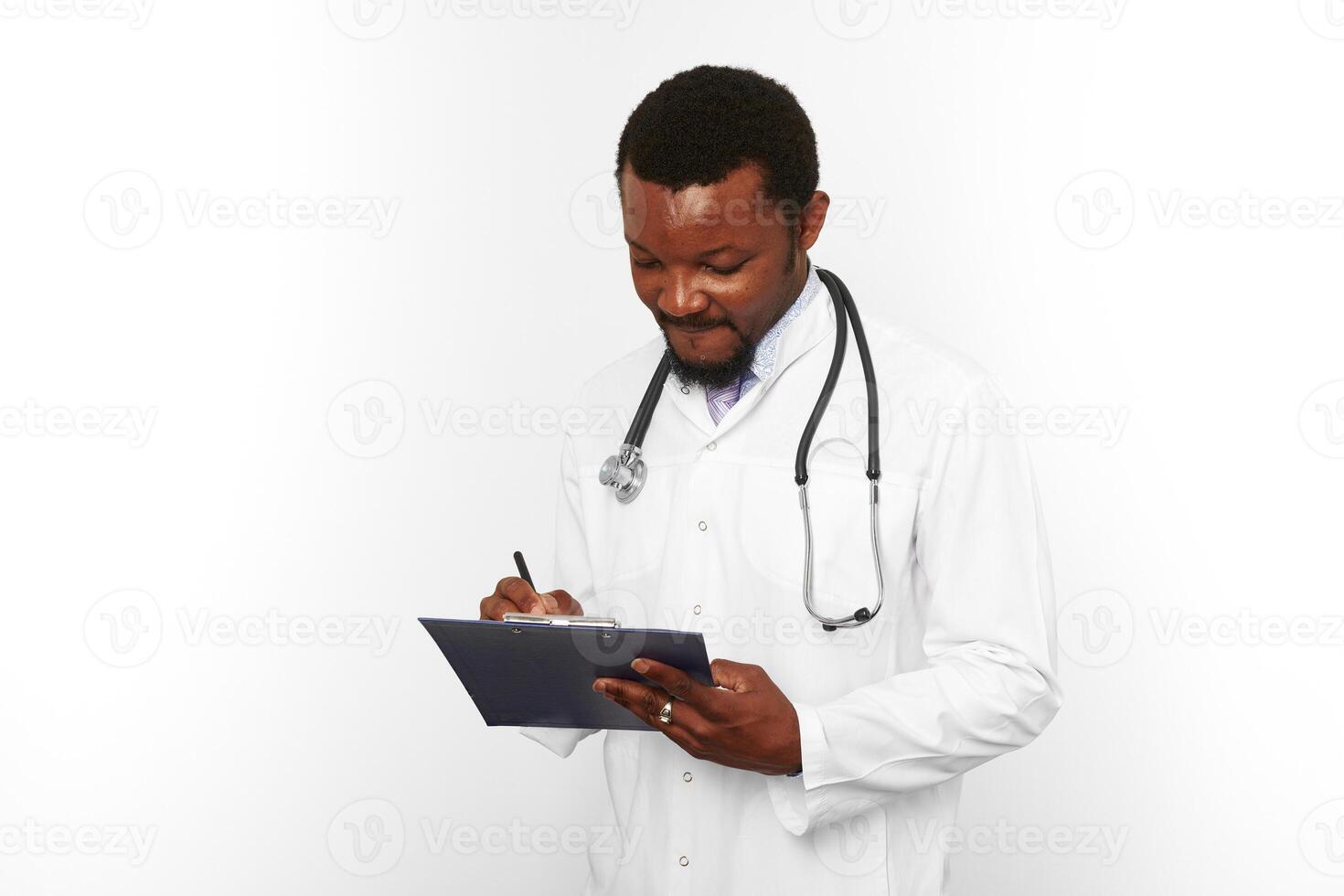 Black bearded doctor man in white coat with stethoscope filling medical records on clipboard photo