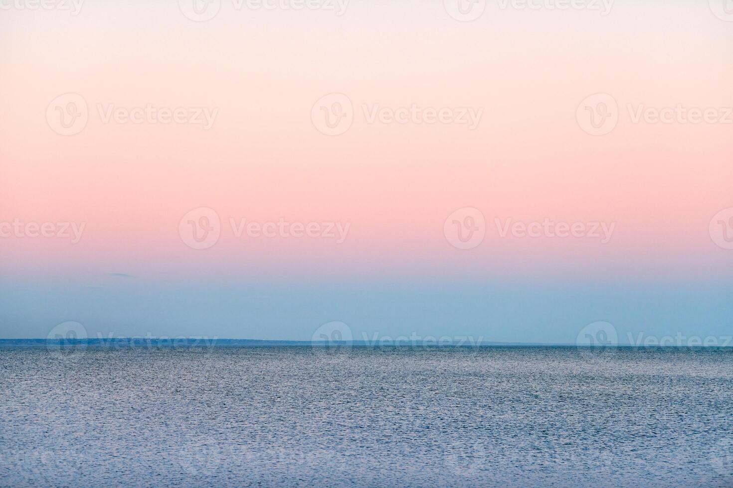 Atmospheric romantic pink red sea sunset sky above blue quiet water, minimalistic peaceful seascape photo