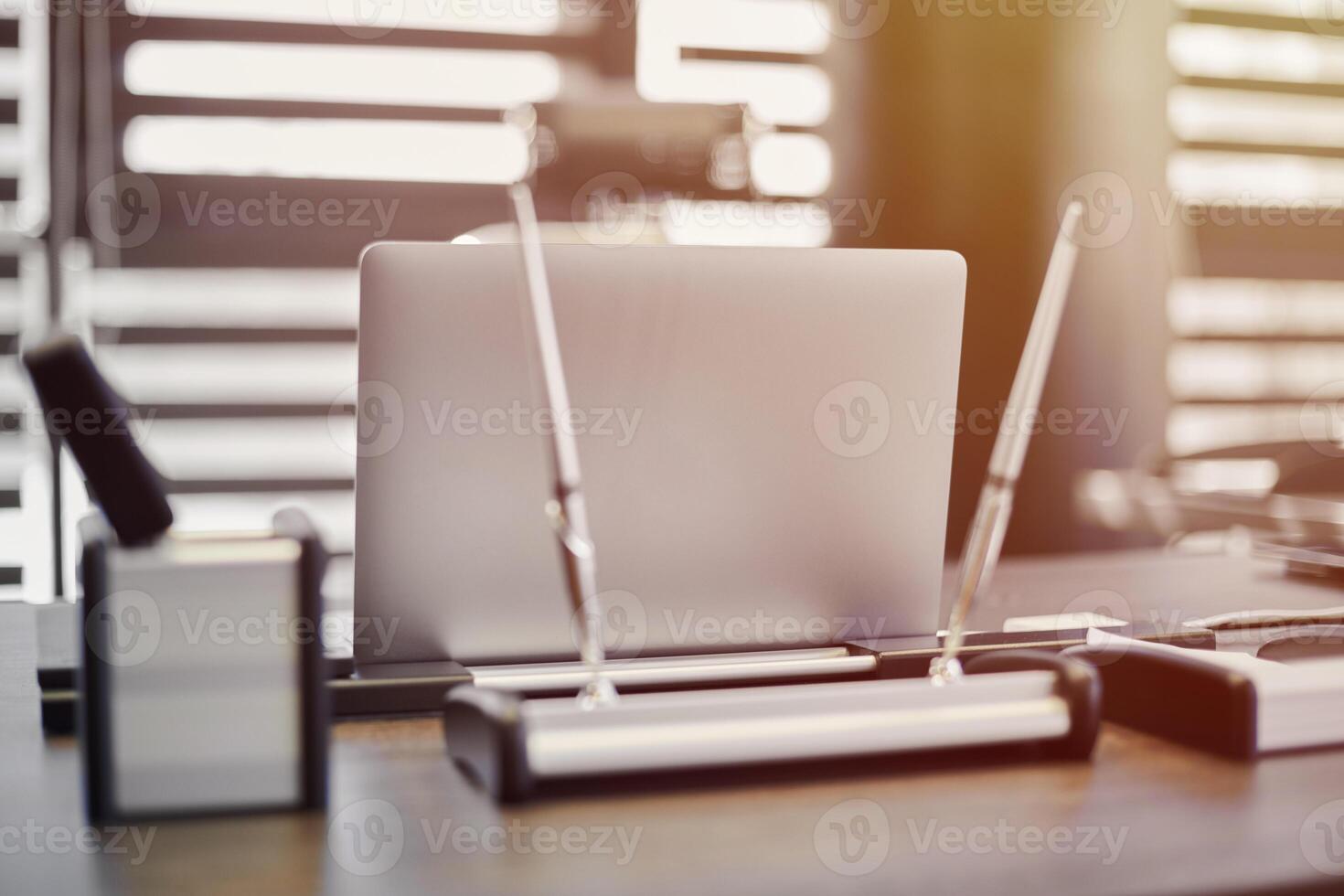 Modern office workplace. Business laptop in work place for chief, boss or other employees. Notebook on work table. Office large corporation. Light through half open blinds photo