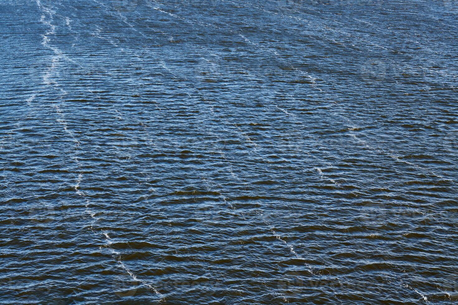 Foam line pollution in river. Factory oil emissions, environmental pollution. Deep blue river with strong current. photo