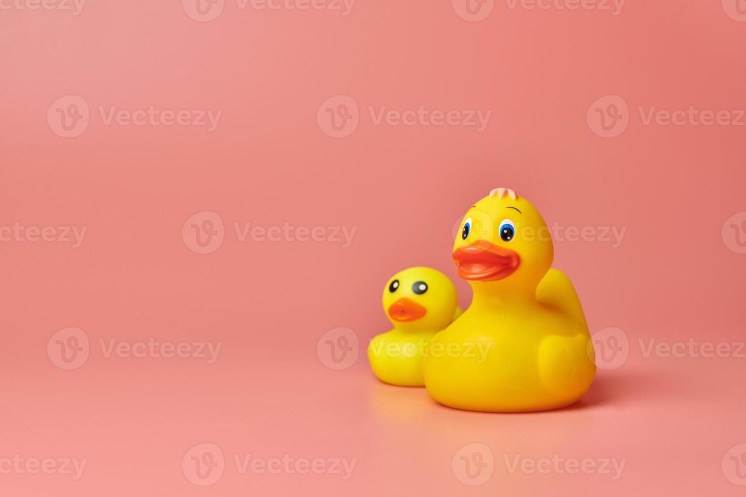 dos juguetes de patos de goma amarillos, espacio de copia. lindos juguetes de baño divertidos, concepto mínimo de niños. fondo rosa foto
