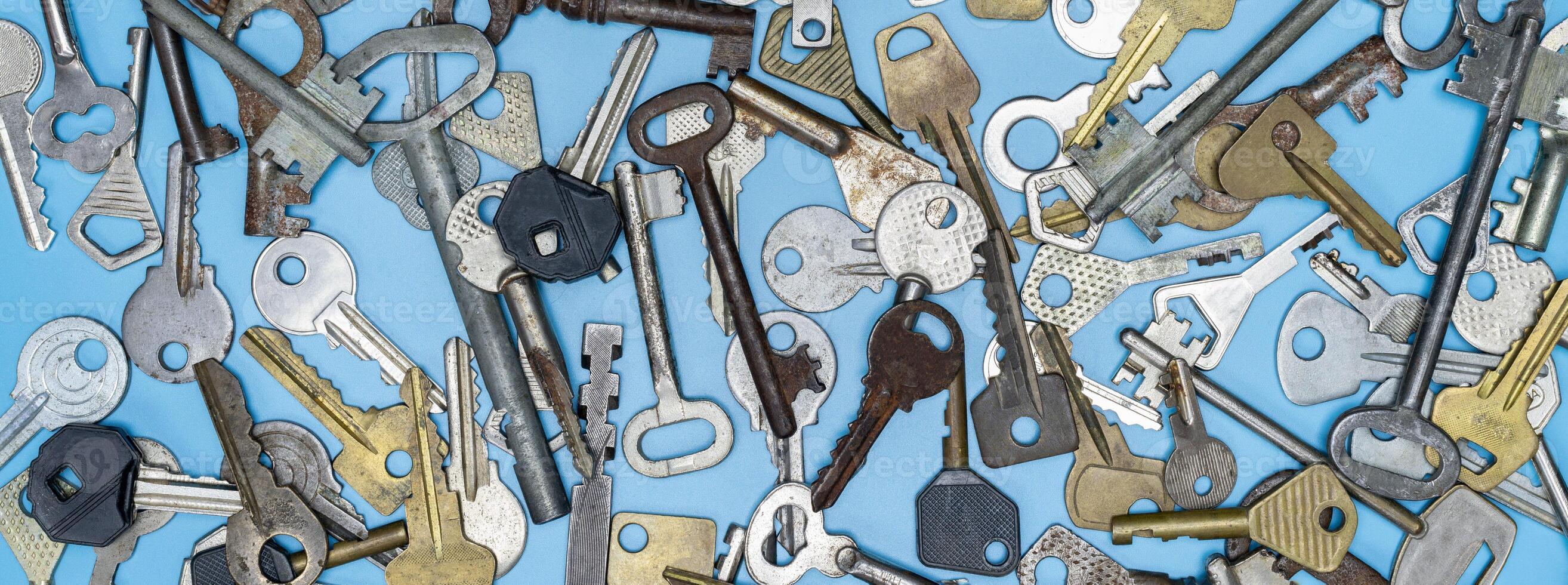 conjunto de llaves sobre fondo azul. llaves de cerradura de puerta y cajas fuertes para la seguridad de la propiedad y la protección de la casa. diferentes tipos de llaves antiguas y nuevas. foto