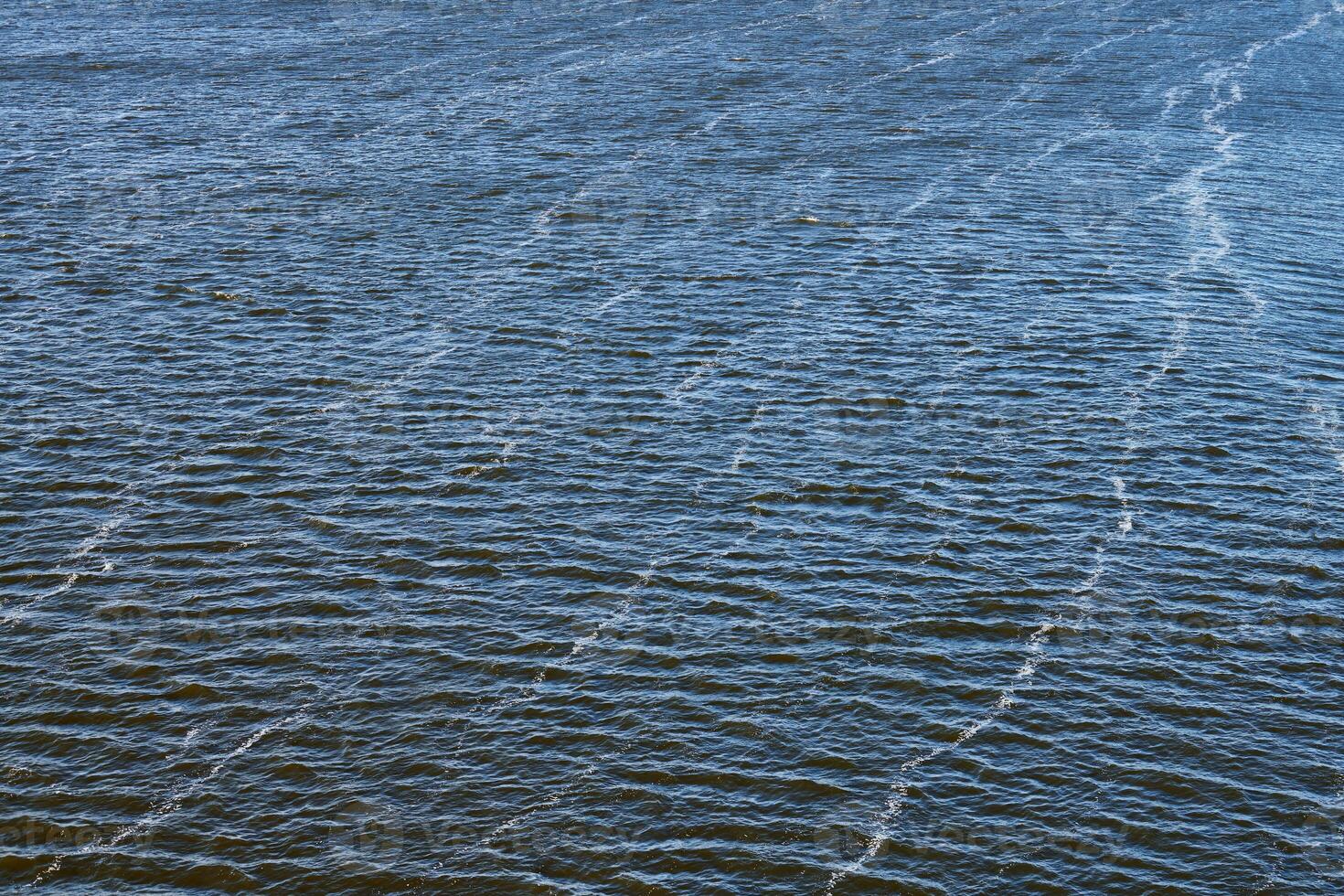Foam line pollution in river. Factory oil emissions, environmental pollution. Deep blue river with strong current. photo