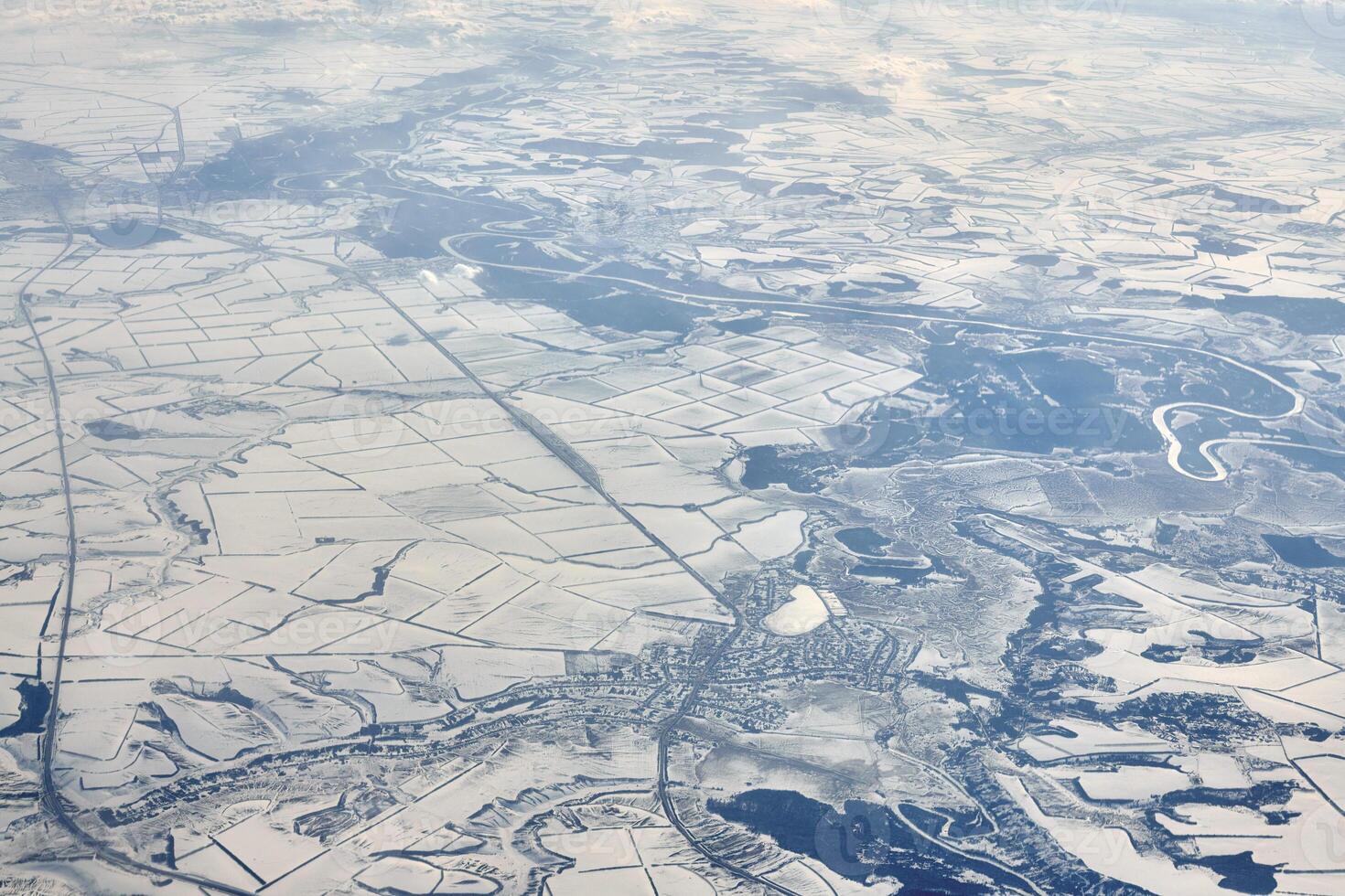 Aerial cloudscape view over clouds top to snow covered rivers, roads, cities and fields, winter air photo