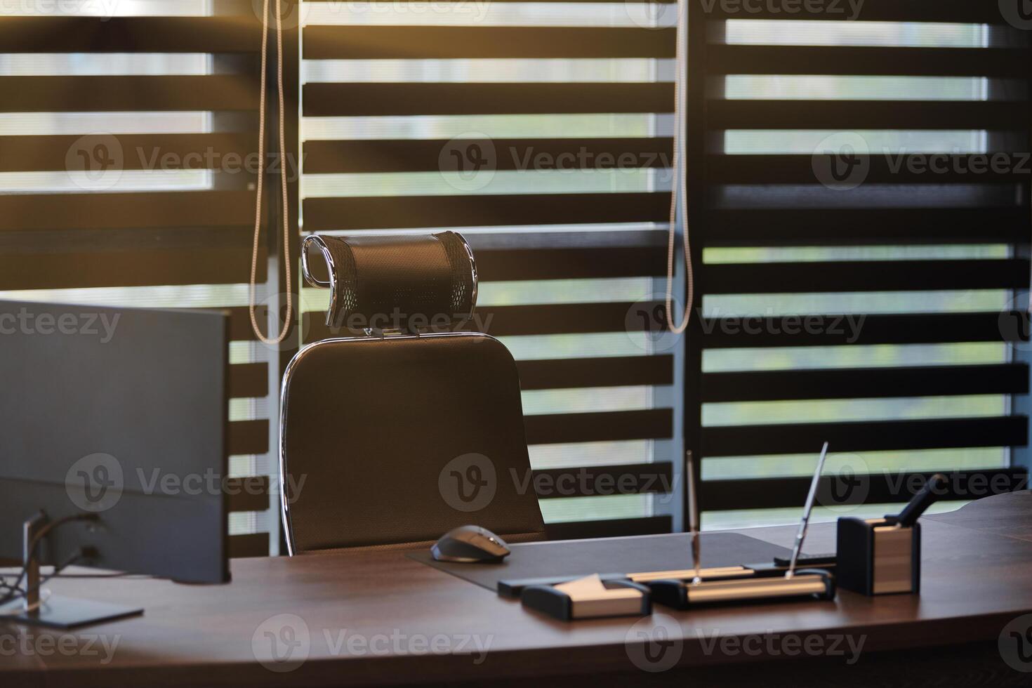 Business office workplace. Sunlight at work place for chief, boss or other employees. Table and comfortable chair. Light through the half open blinds photo