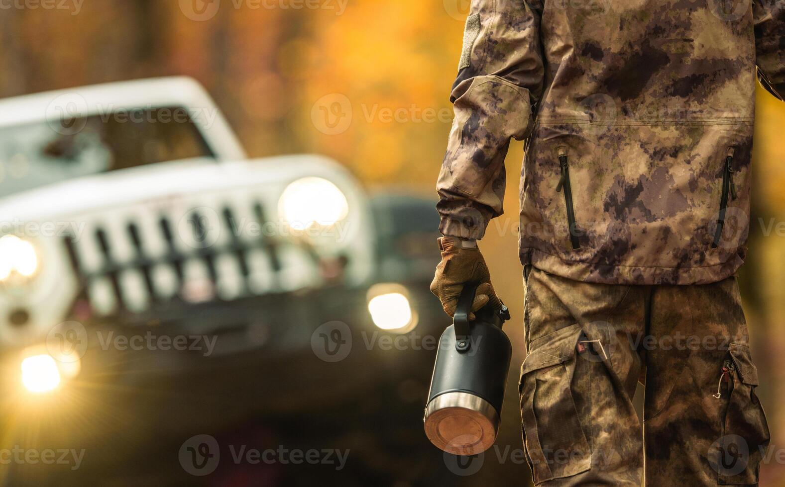 A Man with a Thermos Going to His AWD Vehicle While on a Off Road Trip photo