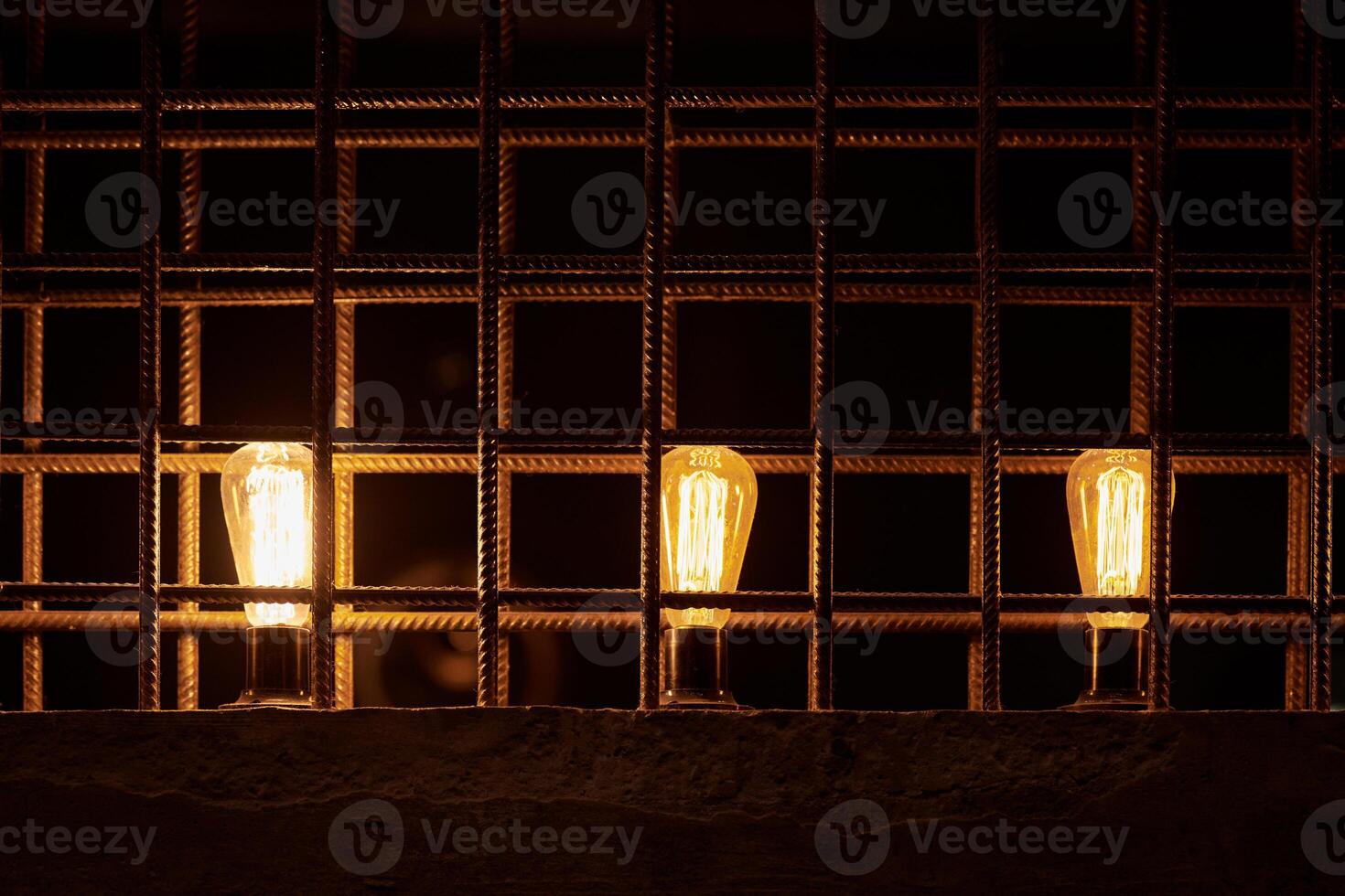 Tres decorativo incandescente ligero bombillas dentro desván dividir desde reforzado acero bar foto
