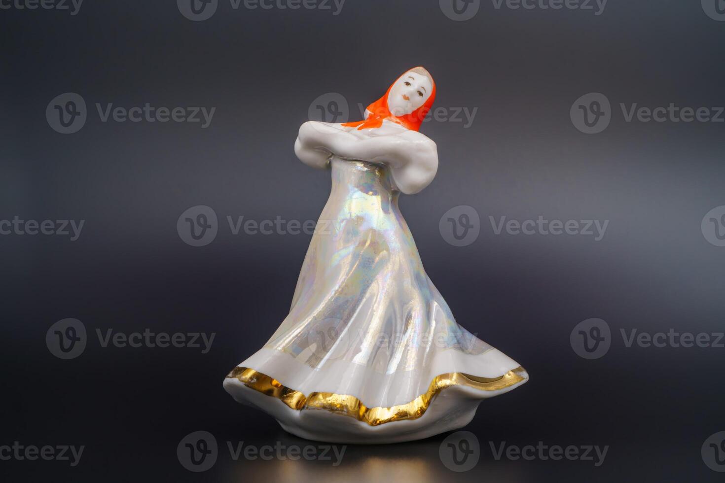 Porcelain Ceramic lady figurine, draped scarf, elegant gown, reflective sheen, crafted finish. Traditional attire, waist sash, green rounded base, bright trousers, folk hand-painted. Black background photo