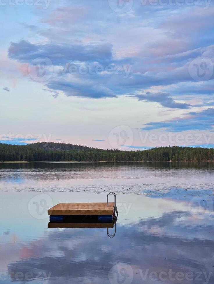 Swimming island in Sweden on a lake at sunset. Clouds reflected in the water. photo