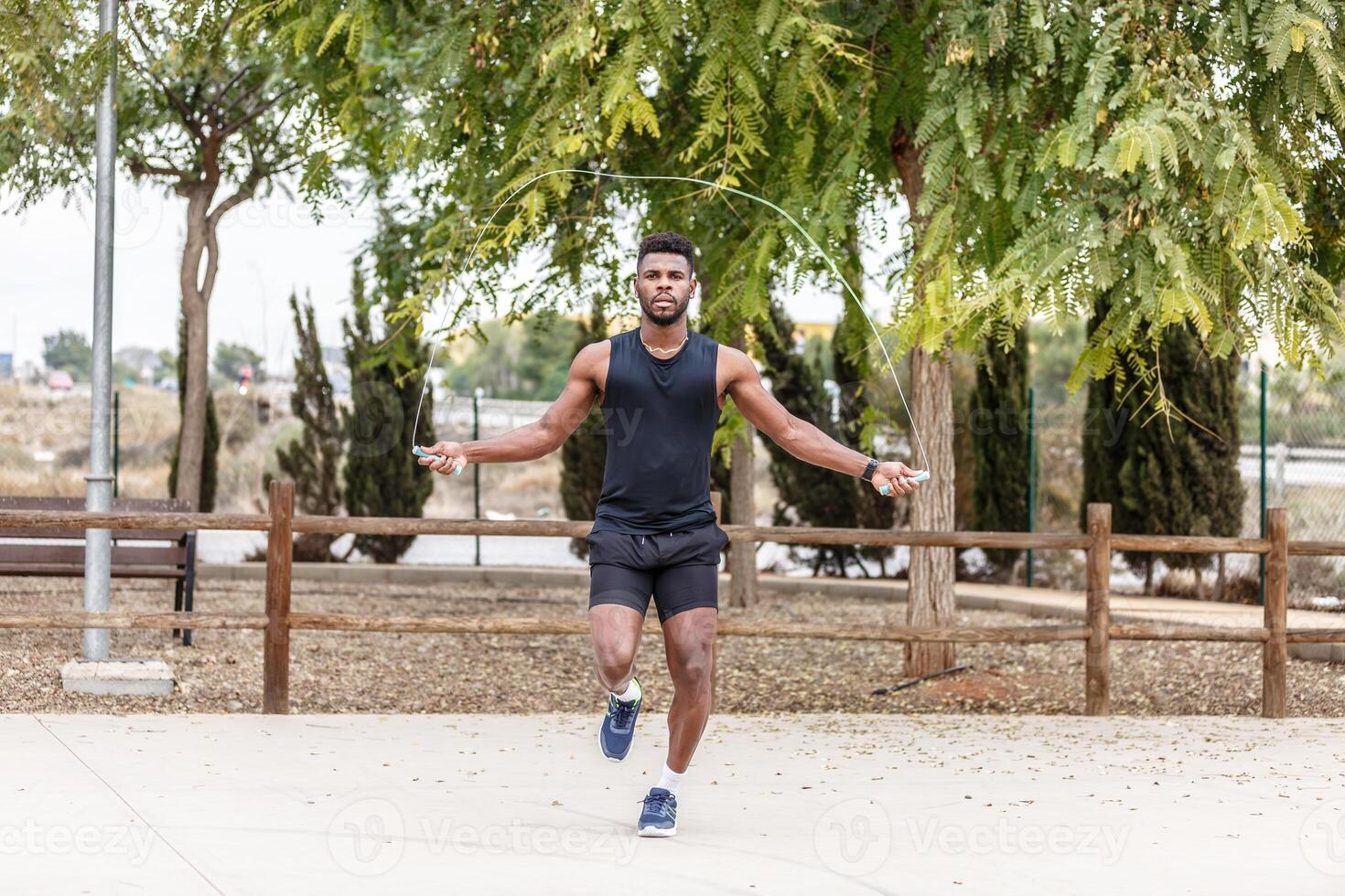 Strong sportsman exercising with skipping rope photo