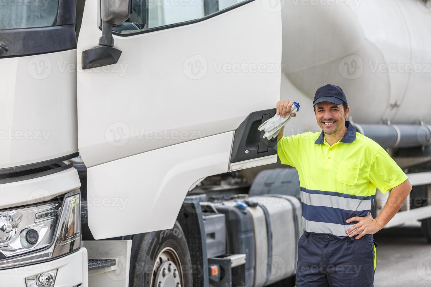 Happy male driver in uniform smiling while standing by truck photo