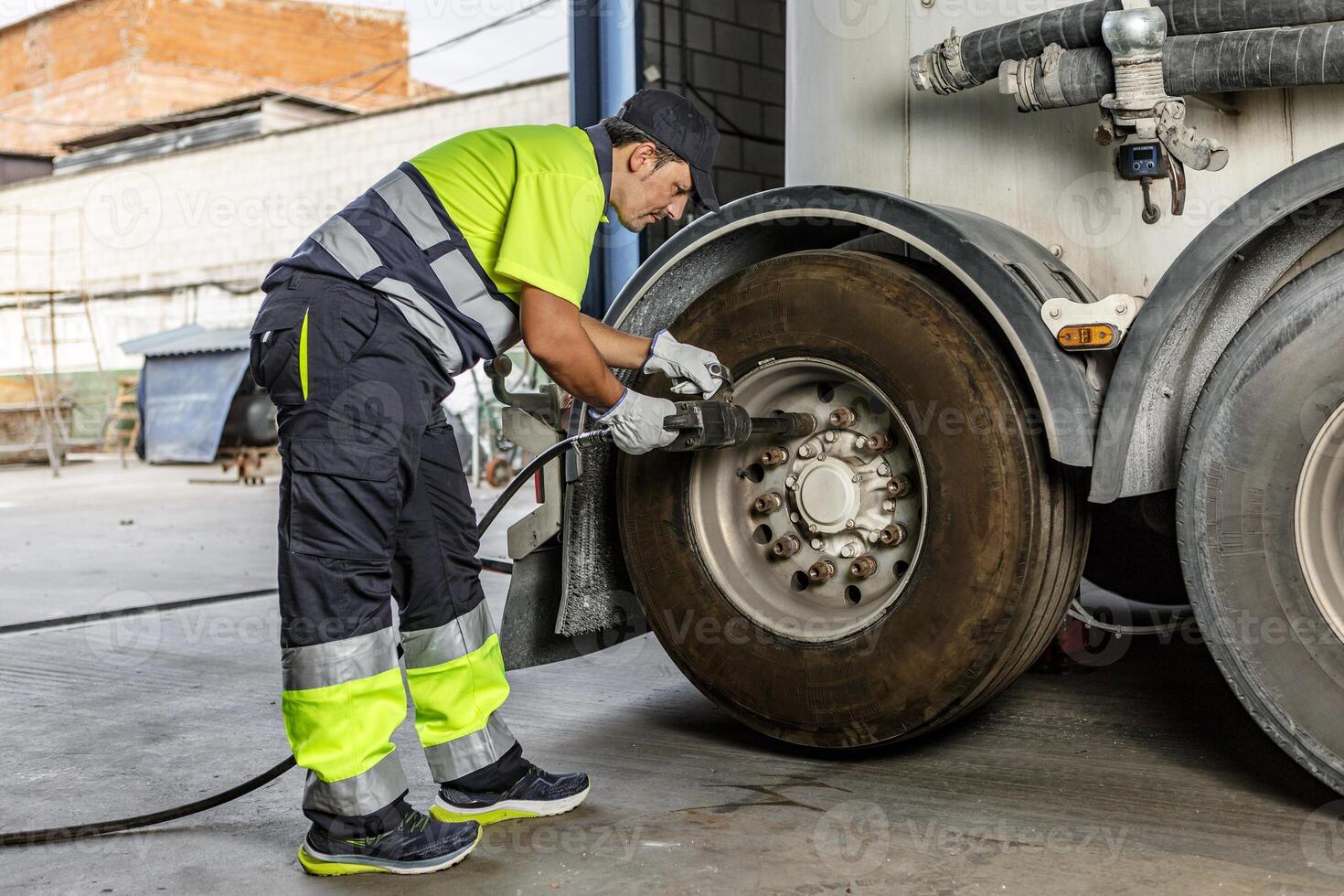 Mechanic tightening wheel of truck in workshop photo