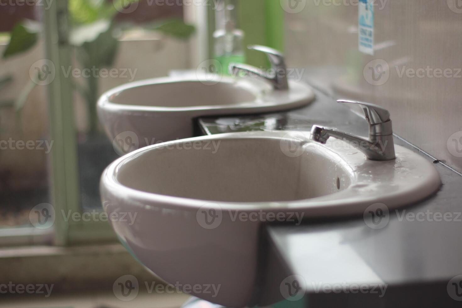 Two washbasin to asia public toilet, Two modern ceramic washbasins, Ceramic sink with chrome mixer in contemporary washroom. photo