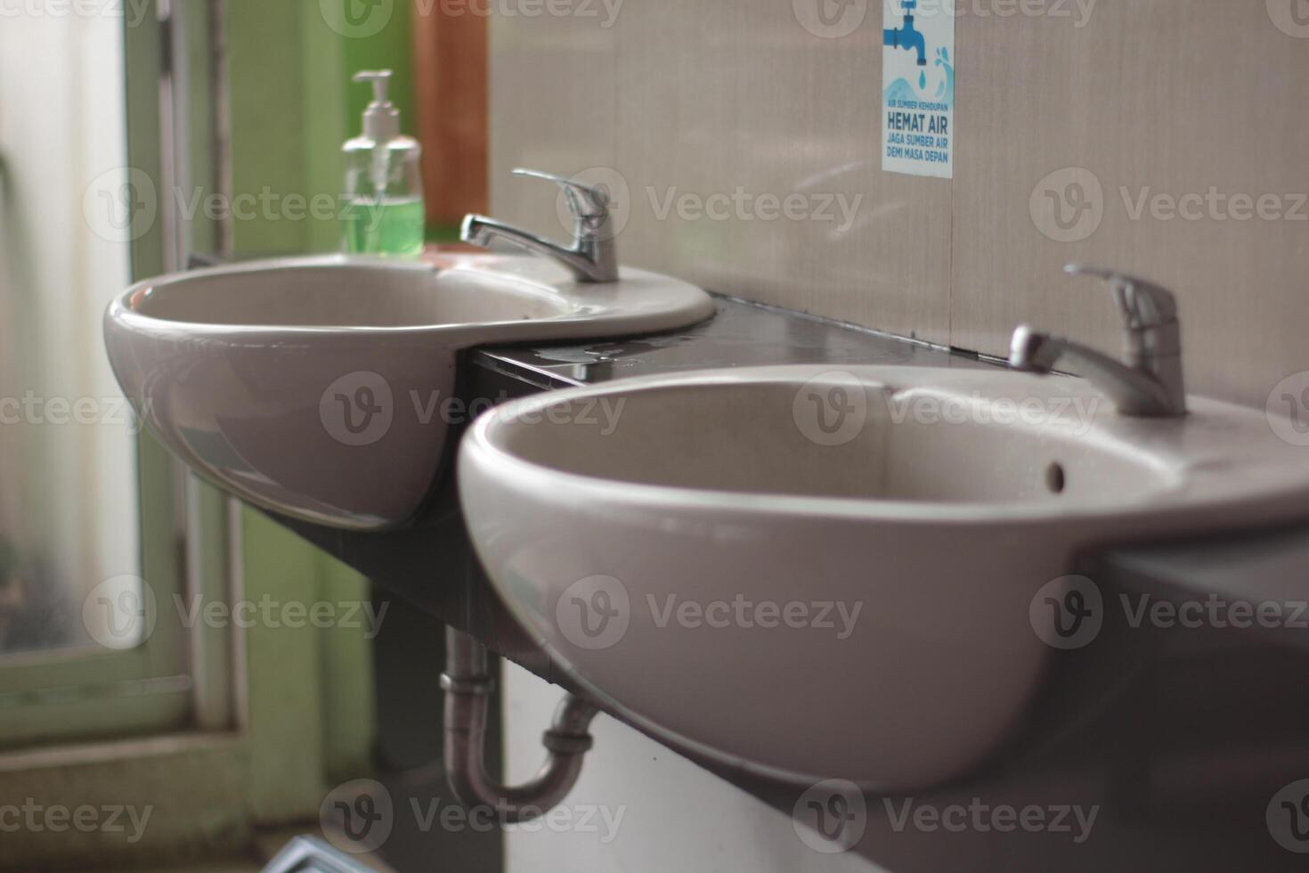 Two washbasin to asia public toilet, Two modern ceramic washbasins, Ceramic sink with chrome mixer in contemporary washroom. photo