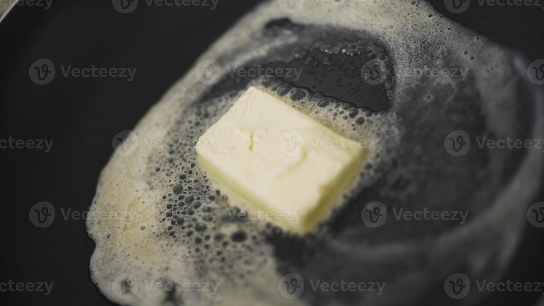 Close-up of piece of butter melting in frying pan. Action. Cooking dish in frying pan with melted piece of butter. Fat butter melts in hot pan photo