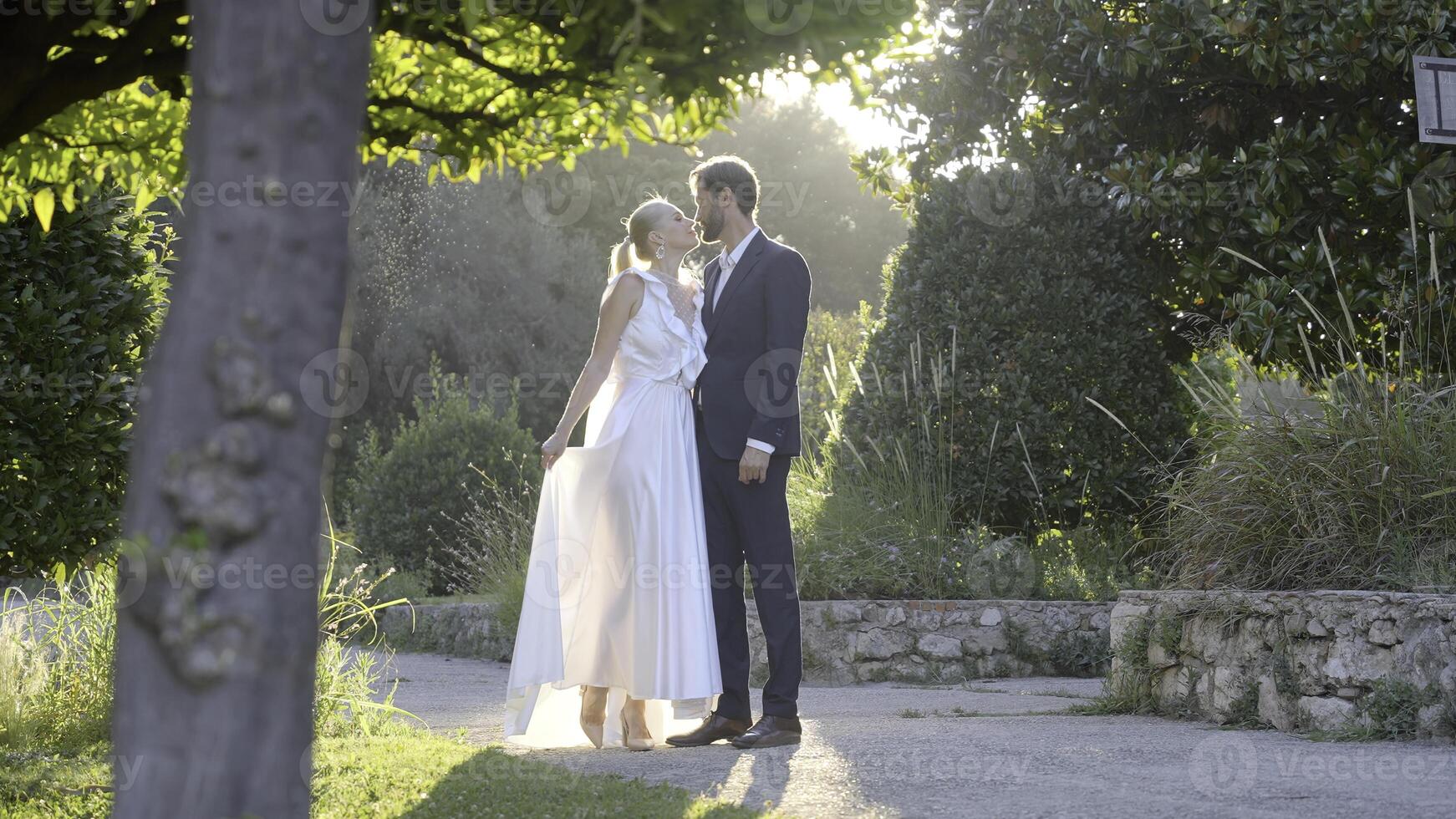 Photo shoot of the bride and groom. Action.The newlyweds are photographed in different places,some posing in the park on the street under the sun,the second on the white staircase,looking at each