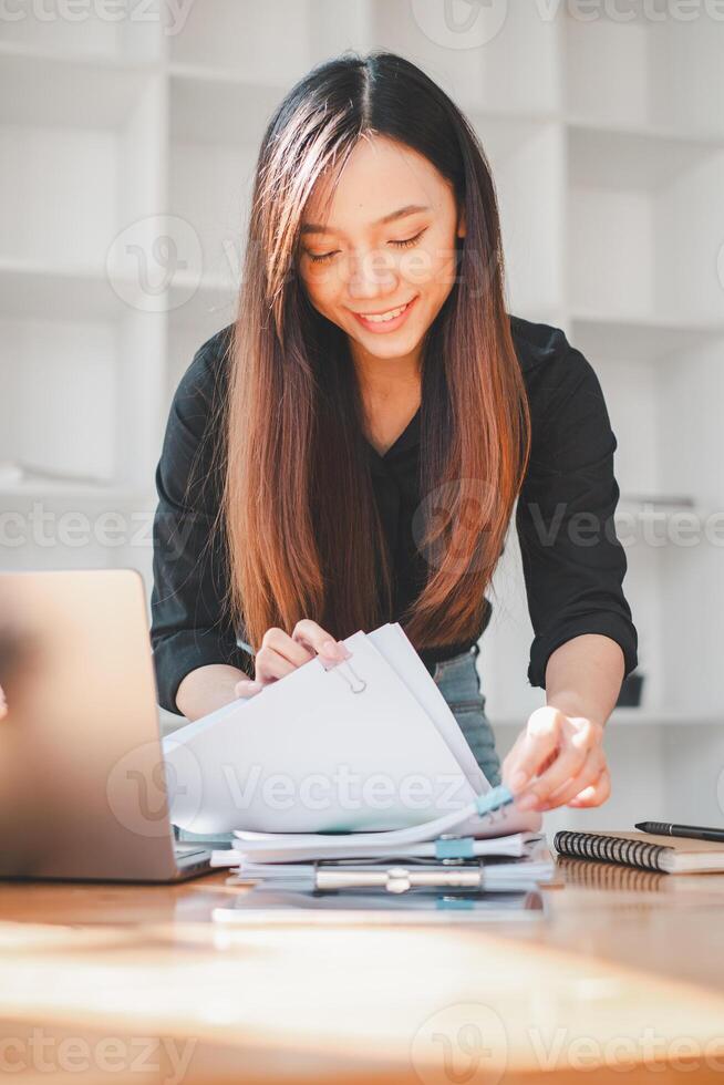 Businesswoman working in Stacks of paper files for searching and checking unfinished document achieves on folders papers at busy work desk office. photo