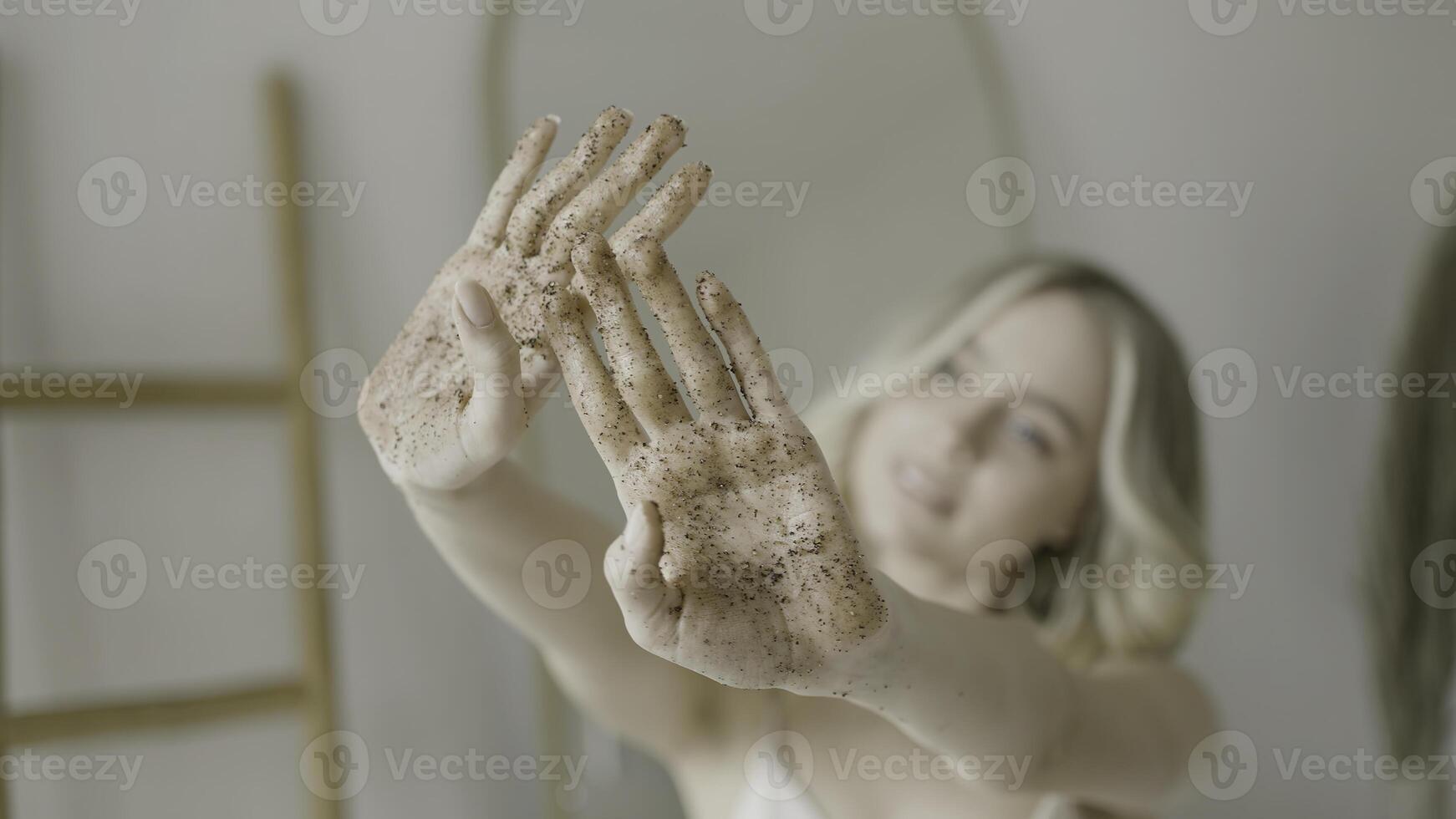 cerca arriba de manos de un bonito rubio niña con café fregar en a ellos. acción. hermosa mujer durante spa procedimiento. foto