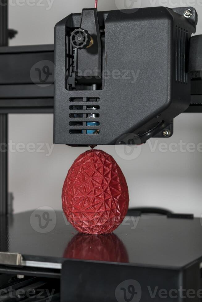 Close up of a 3d printer printing a red polygonal egg photo