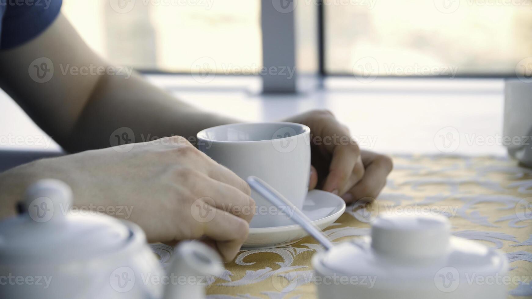 Close up mans hands with cup of coffee on the table and window background. Businessman coffee break closeup, hands with americano cup on wood table, close up photo