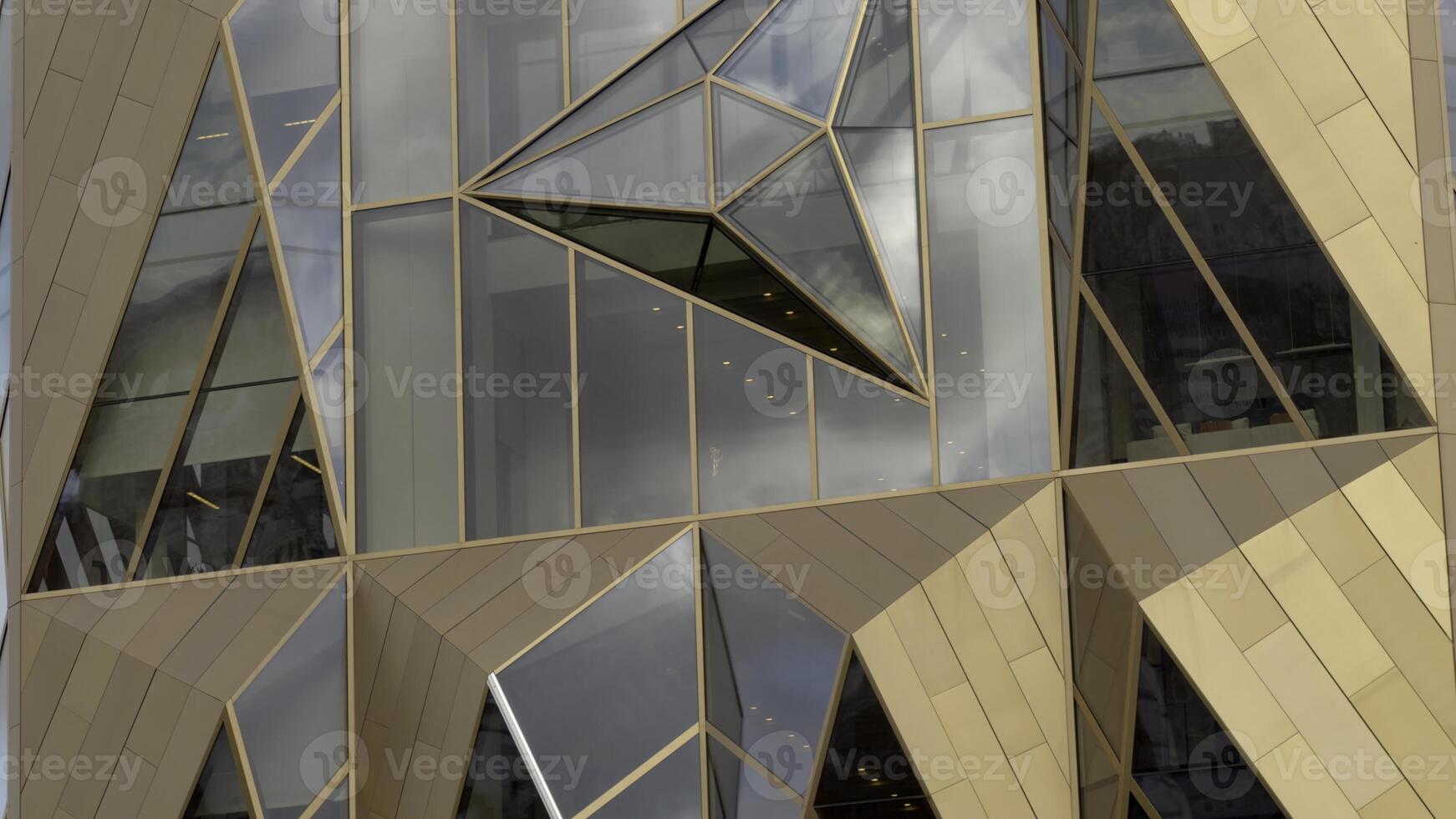 Flying around the complex geometric shaped modern building with mirrored windows. Stock footage. Construction with unusual architecture, skyscraper, office block in business district of big city. photo