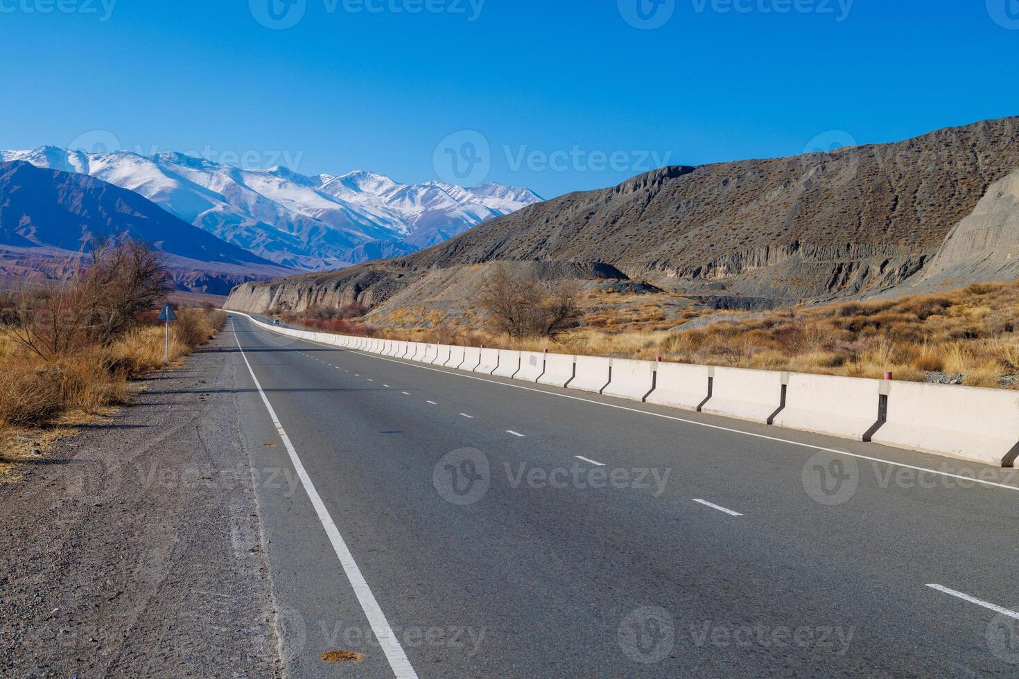 empty highway road with separating concrete barrier in mountains at sunny autumn day photo