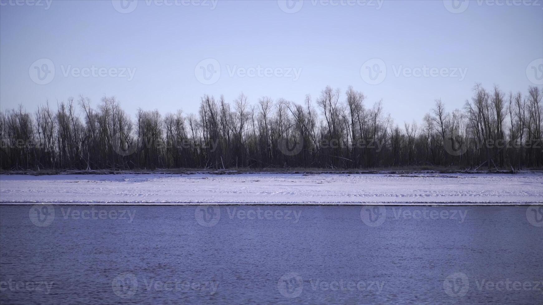 Shoreline of river with ice in spring. Clip. Beautiful beach with water and ice on winter day. River with ice near shore on sunny winter day photo
