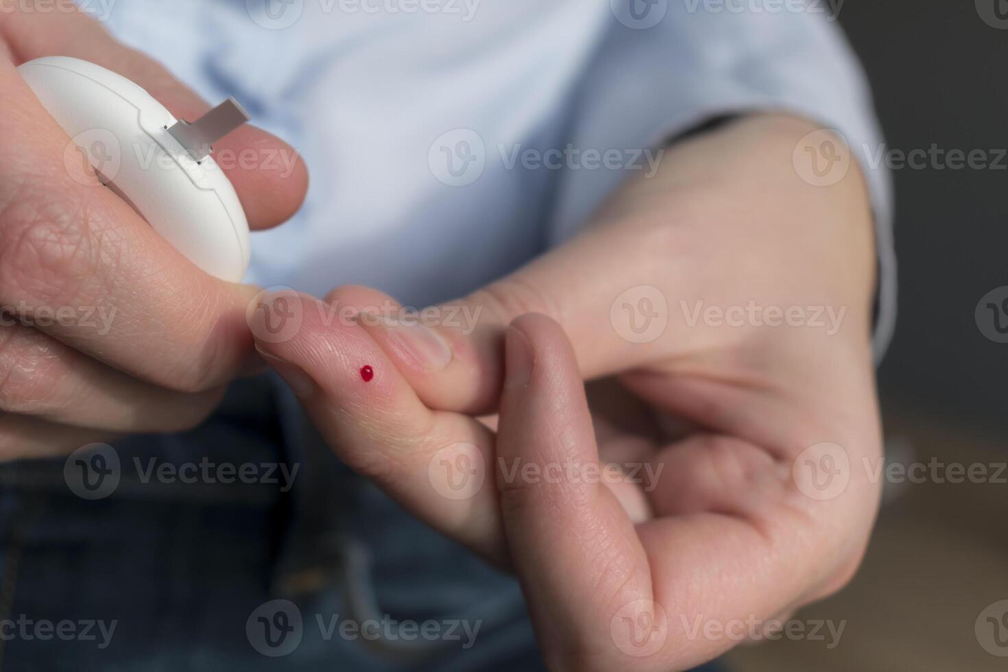 Woman pricking her finger to check blood glucose level with glucometer, test blood glucose for diabetes photo