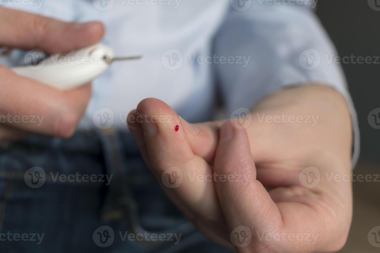 Woman pricking her finger to check blood glucose level with glucometer, test blood glucose for diabetes photo