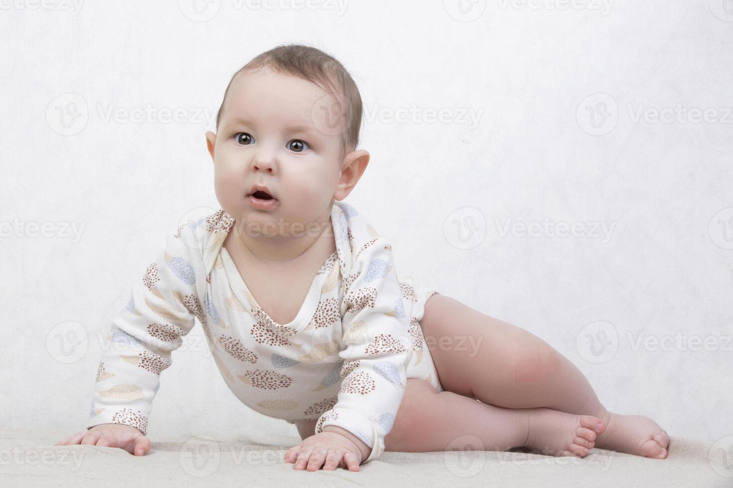 Kid with a smile on a white background. A healthy six-month-old boy lies on the bed. Conceptual photo of fatherhood and motherhood.