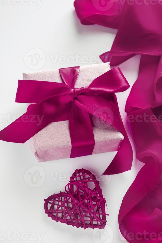 Gift box with craft paper and red ribbon on a white background photo