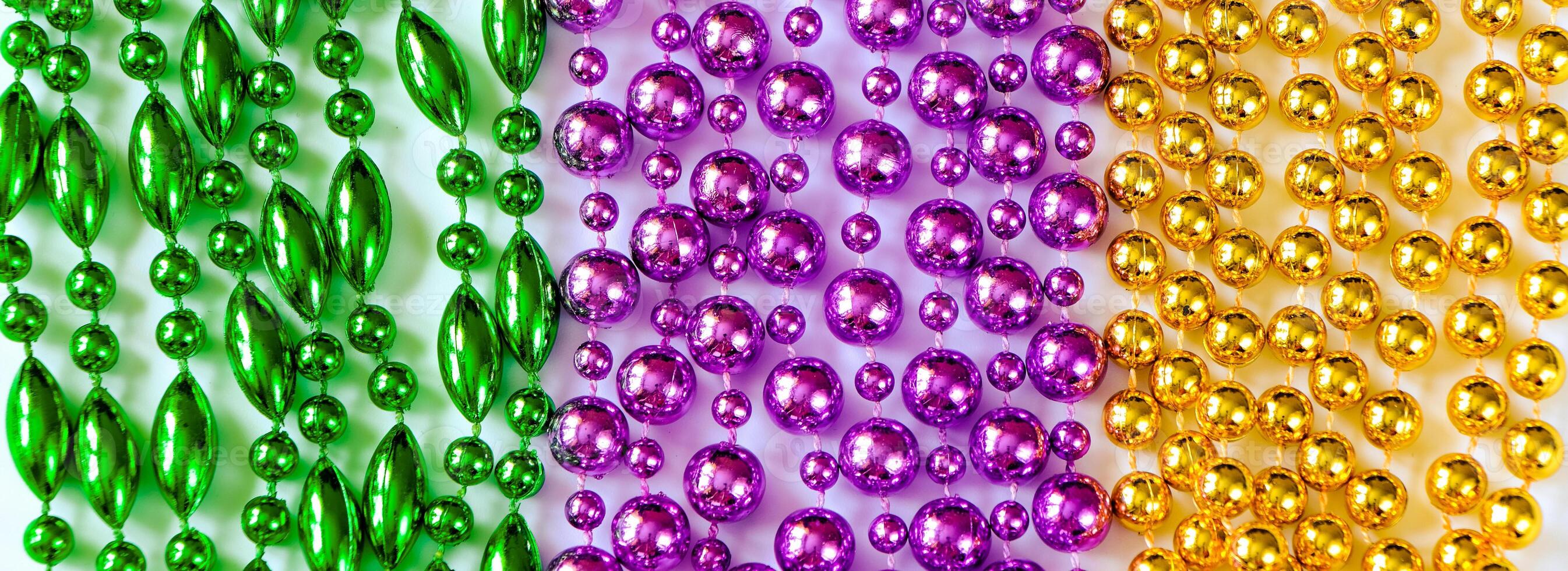 Mardi Gras background. Multi-colored beads close-up. Festive decorations in gold, green and purple colors. Fat Tuesday symbol. photo