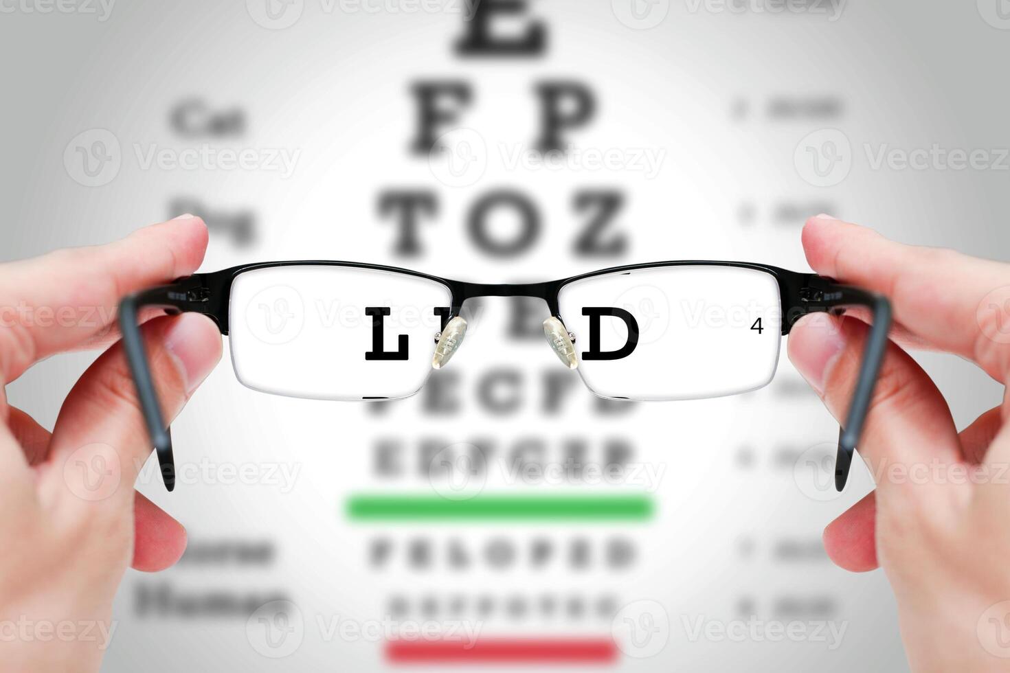 Female hand holding glasses with eyesight test on chart board. photo