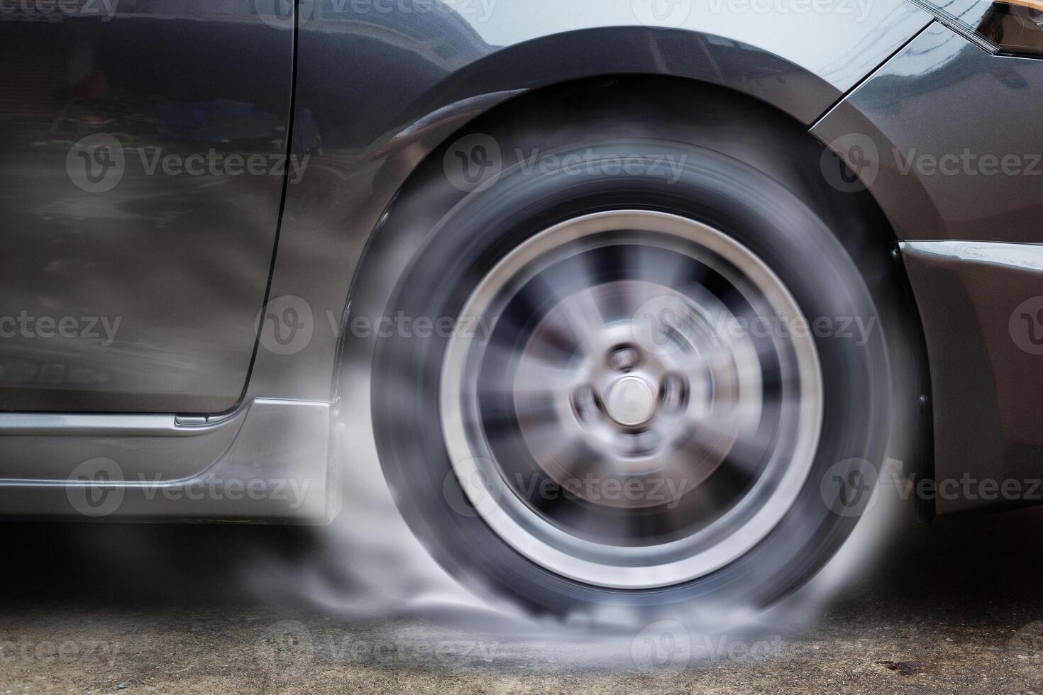Car racing spinning wheel burns rubber on floor. photo