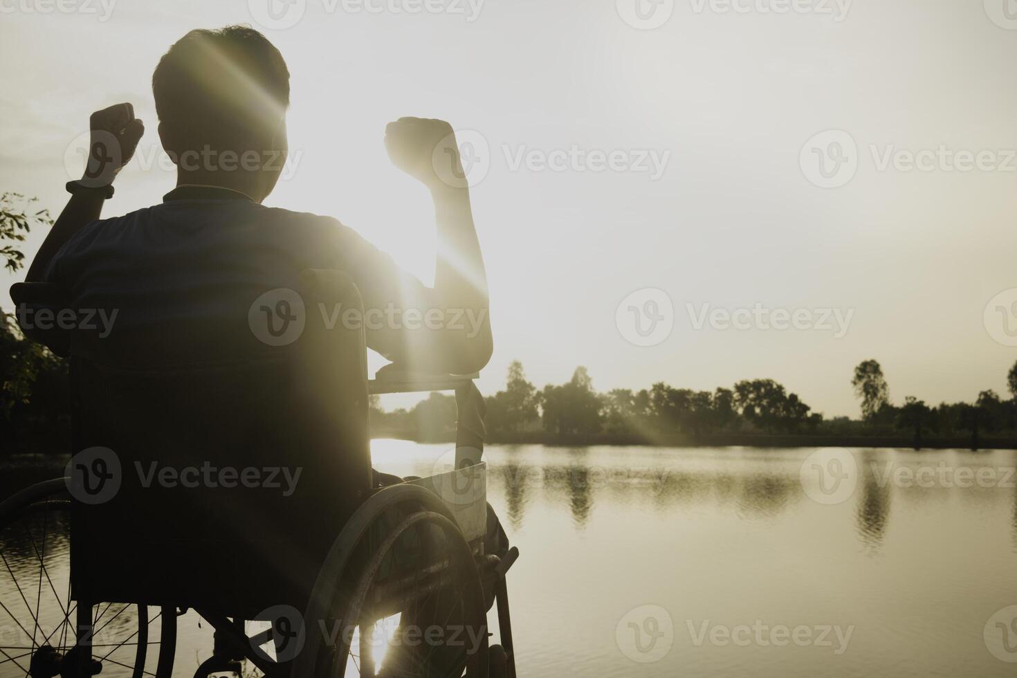 silueta joven discapacitado hombre viendo río fondo.él es aumento un mano a y sentado en silla de ruedas.desesperación,solitaria,esperanza.photo concepto depresión y paciente. foto