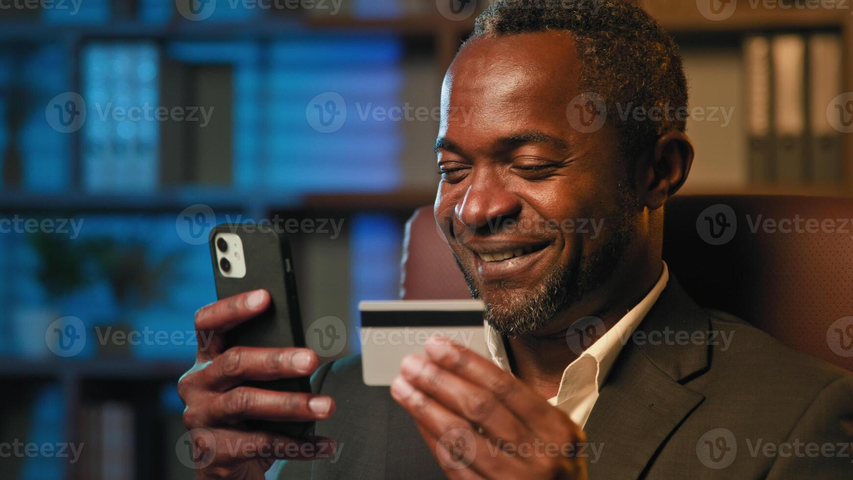 Smiling african american businessman hold credit card remote pay for purchase goods or service on Internet man manage personal bank account on smartphone payment using mobile banking app safe transfer photo