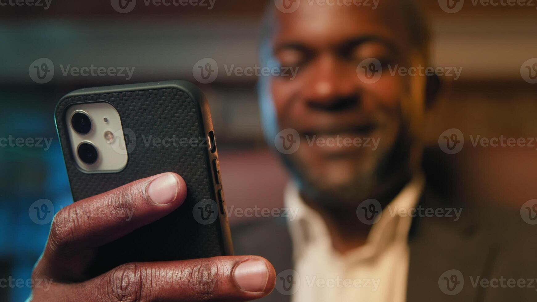 Blurred focus african american businessman holding smartphone browsing social network writing email message happy man chatting remotely communicating with client using mobile phone close-up telephone photo