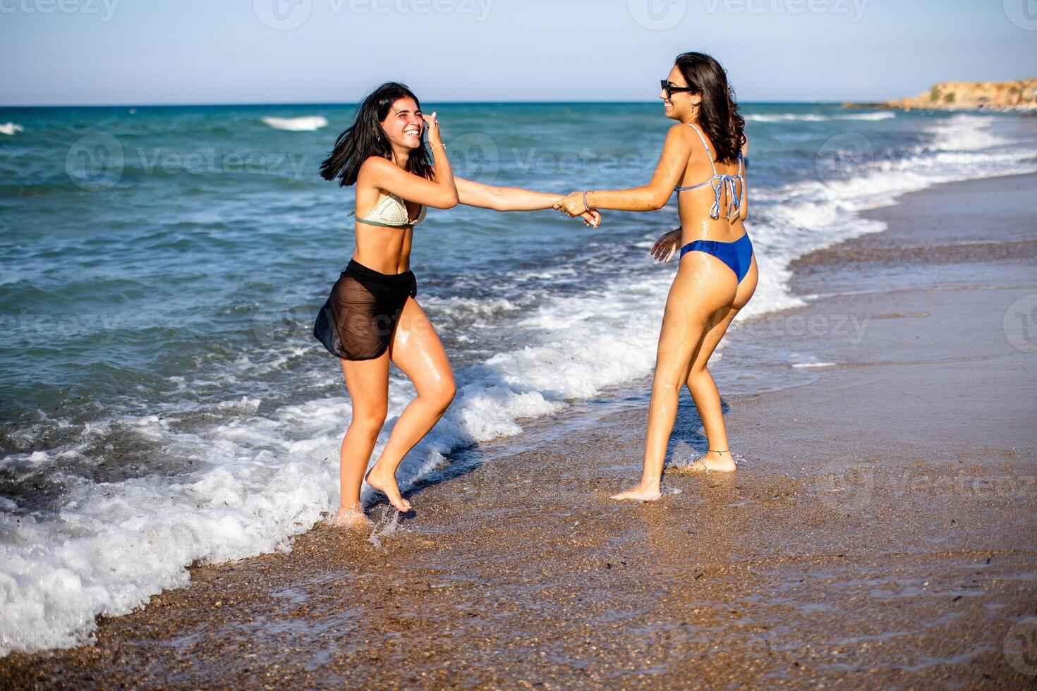 Two pretty young woman having fun on the seaside photo