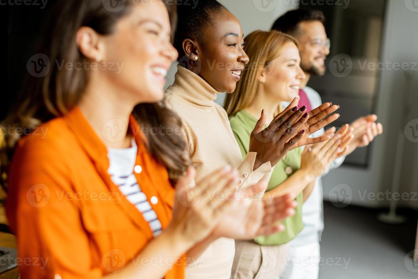 Young multiethnic startup team standing and applauding in the modern office photo