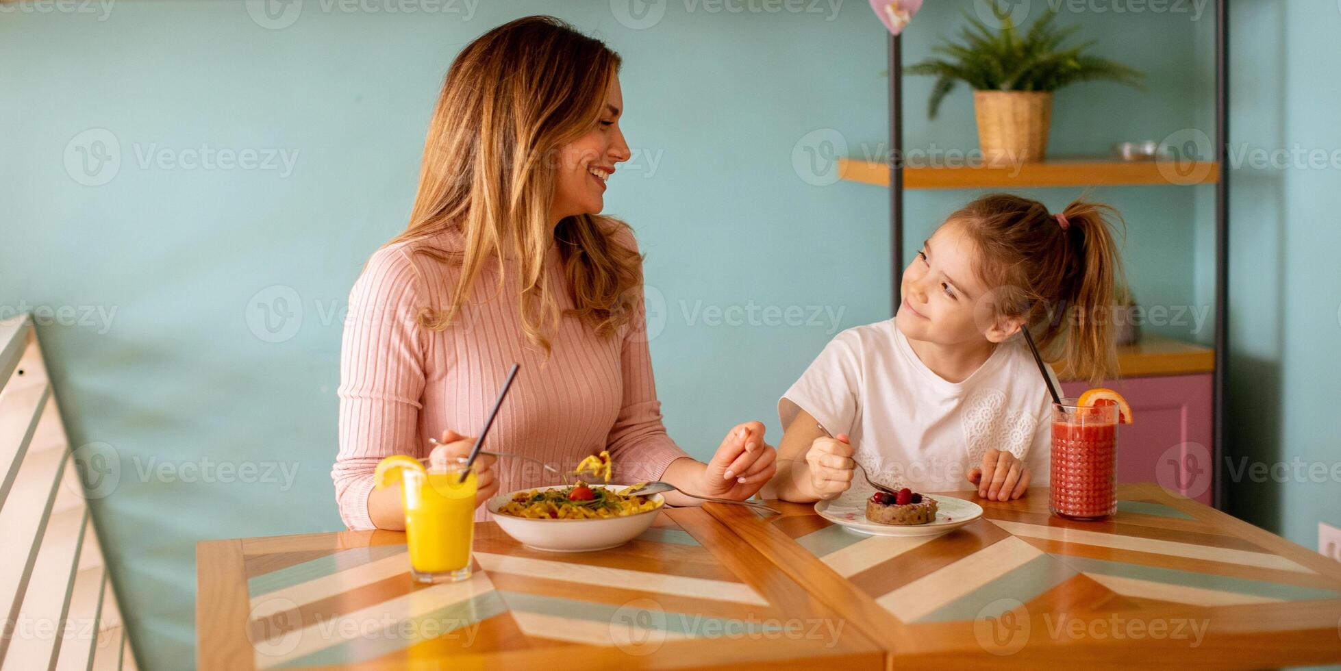 madre y hija teniendo un desayuno con Fresco exprimido jugos en el café foto