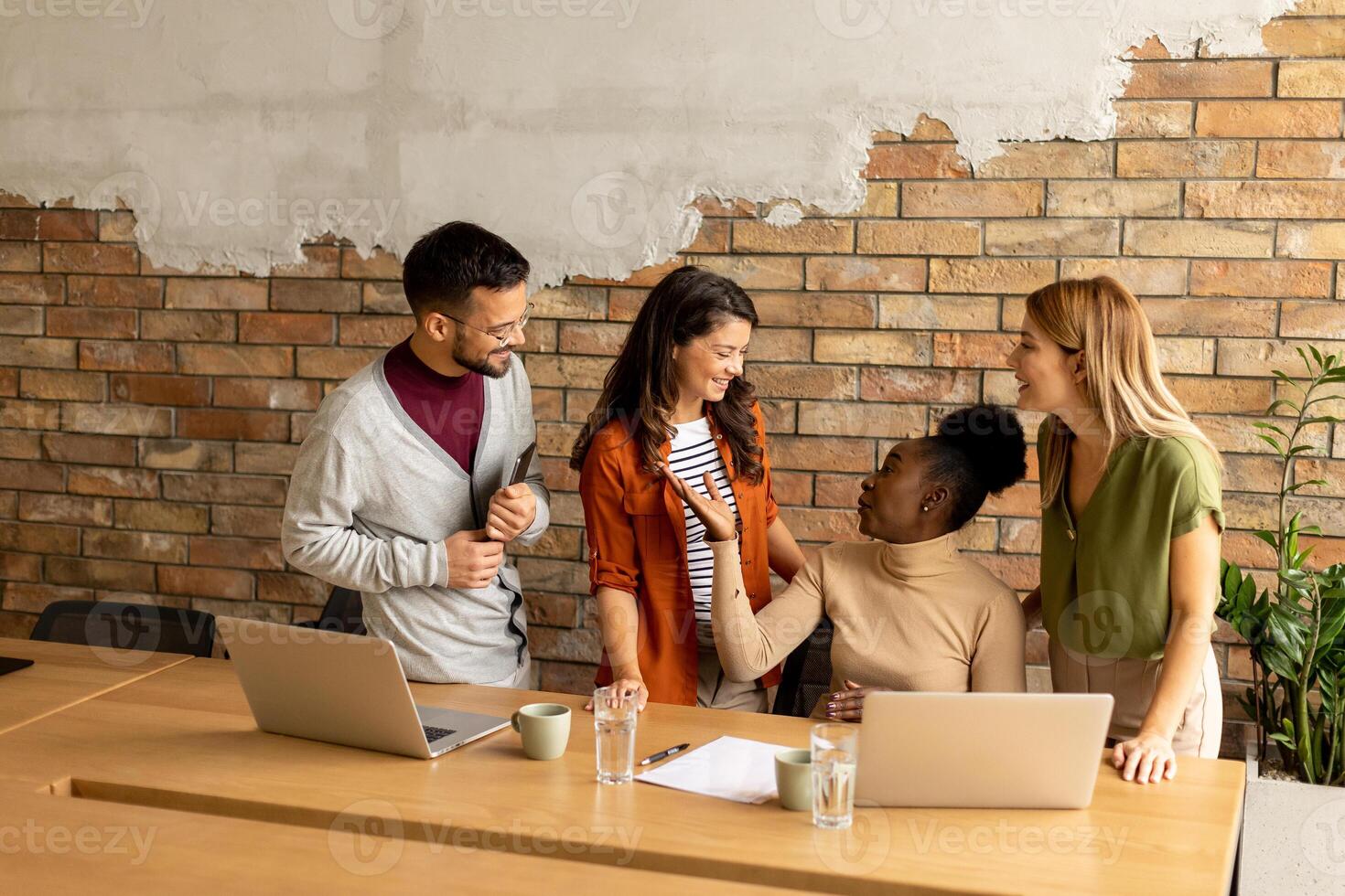 Young multiethnic startup team working by the brick wall in the industrial style office photo