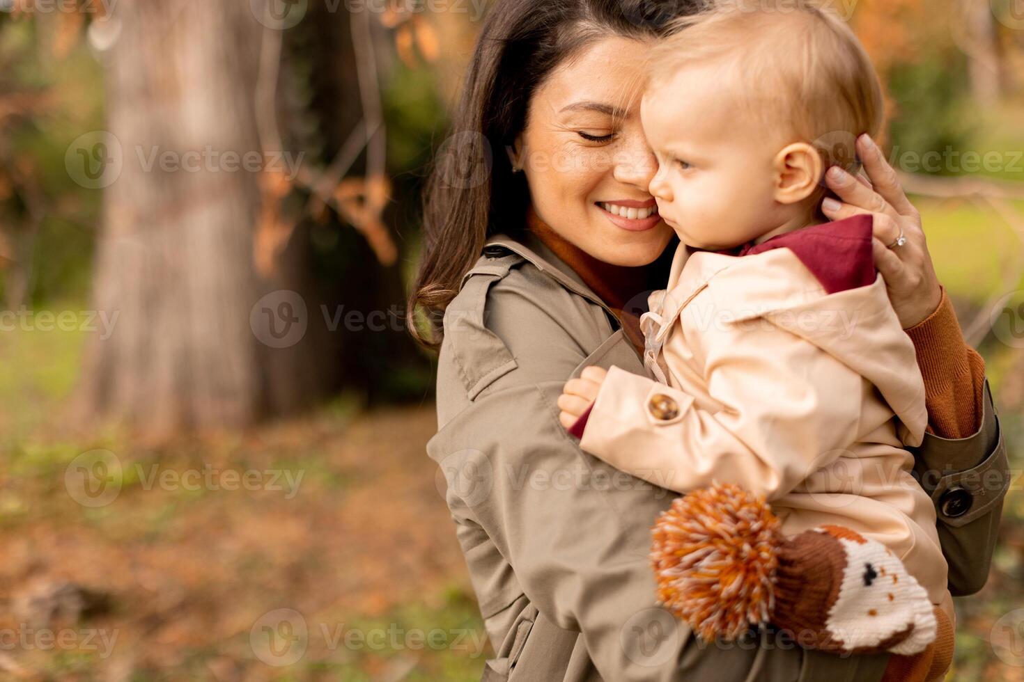 Young woman holding cute baby girl in the autumn park photo