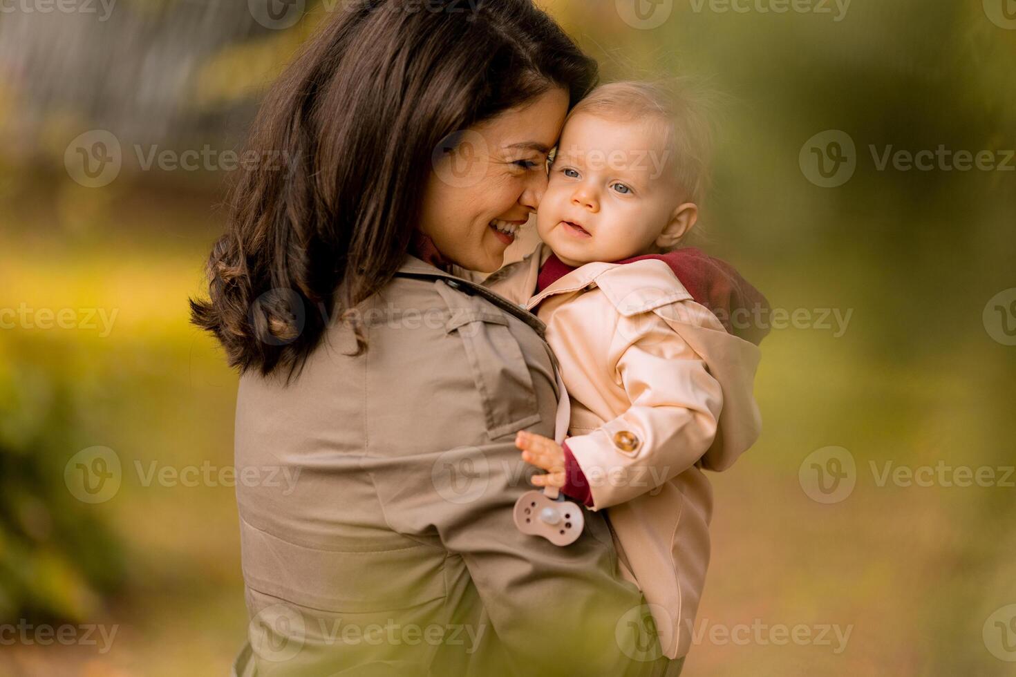 Young woman holding cute baby girl in the autumn park photo