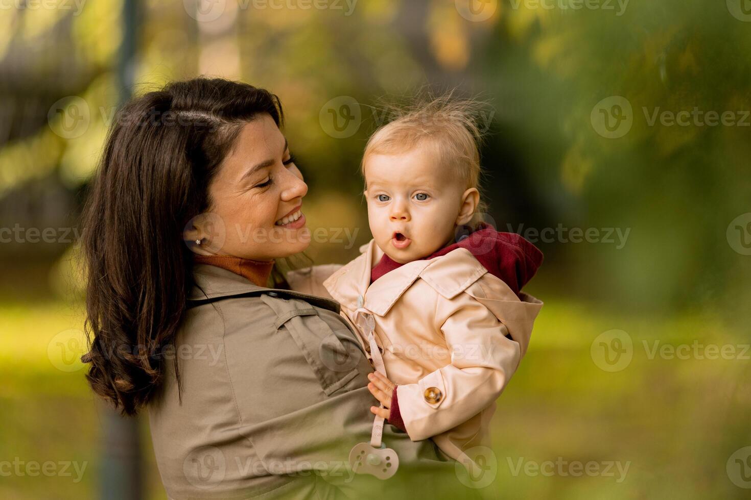 Young woman holding cute baby girl in the autumn park photo