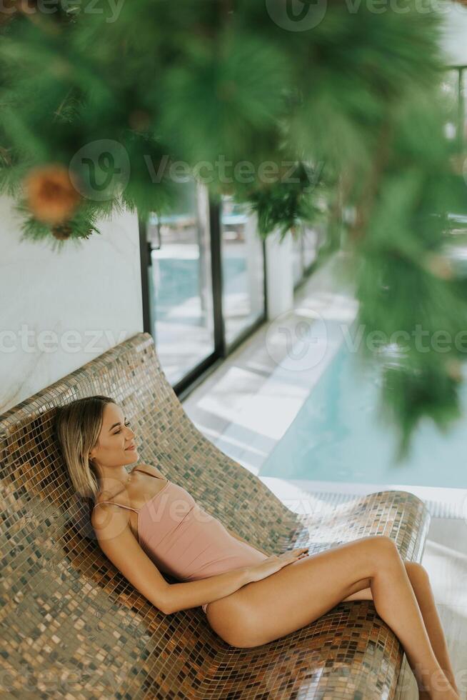 joven mujer relajante por el interior nadando piscina foto