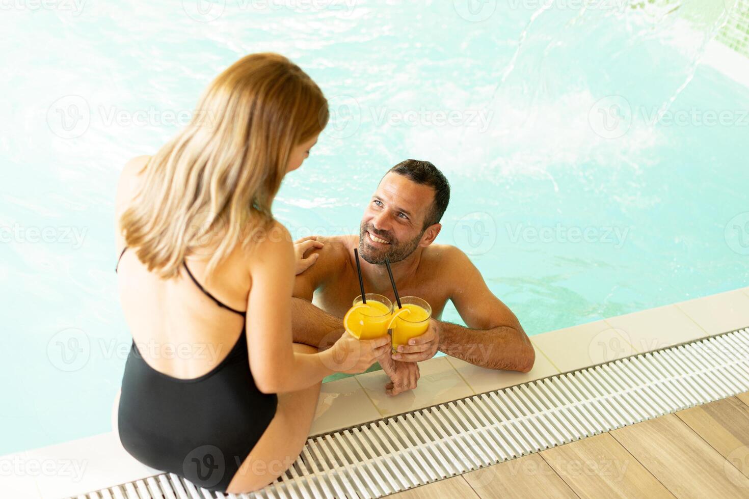 Young couple relaxing by the indoor swimming pool photo