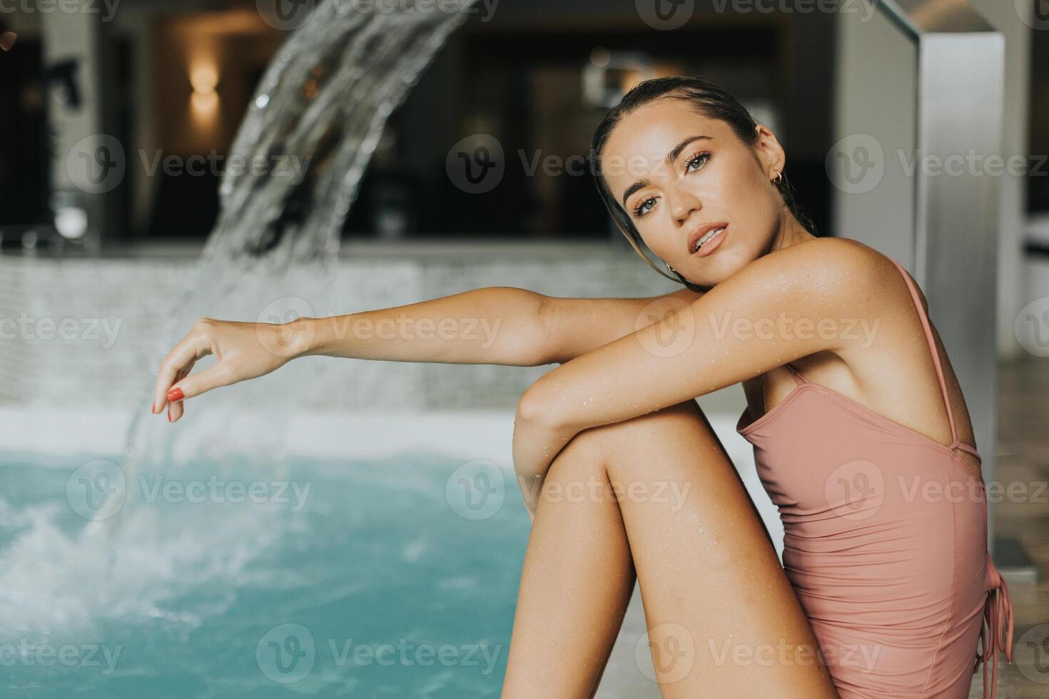 Young woman relaxing by the indoor swimming pool photo