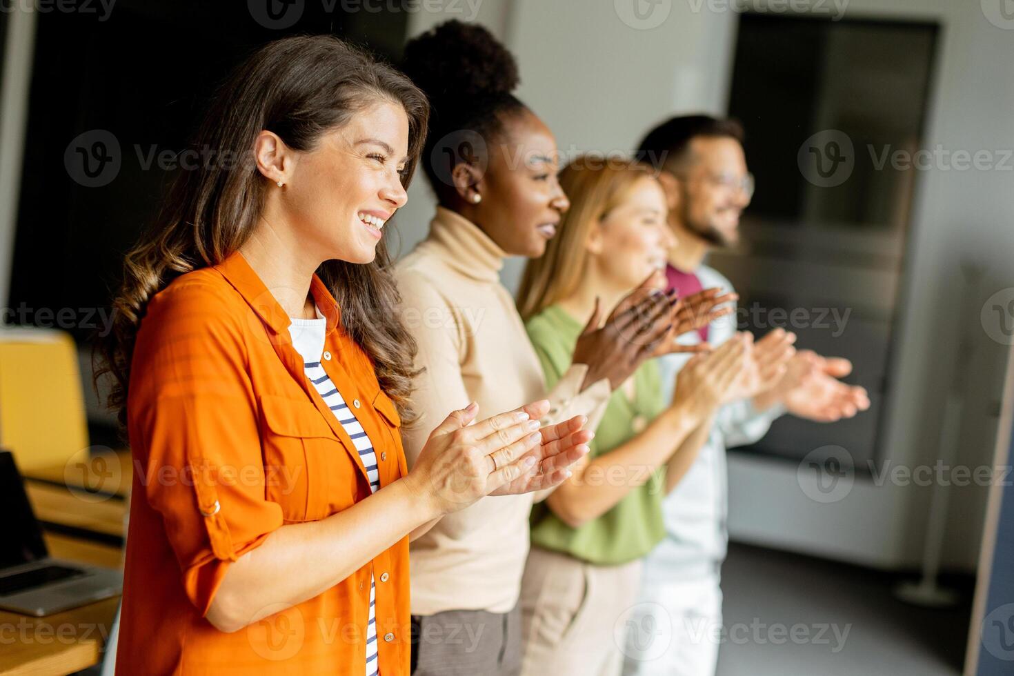 Young multiethnic startup team standing and applauding in the modern office photo