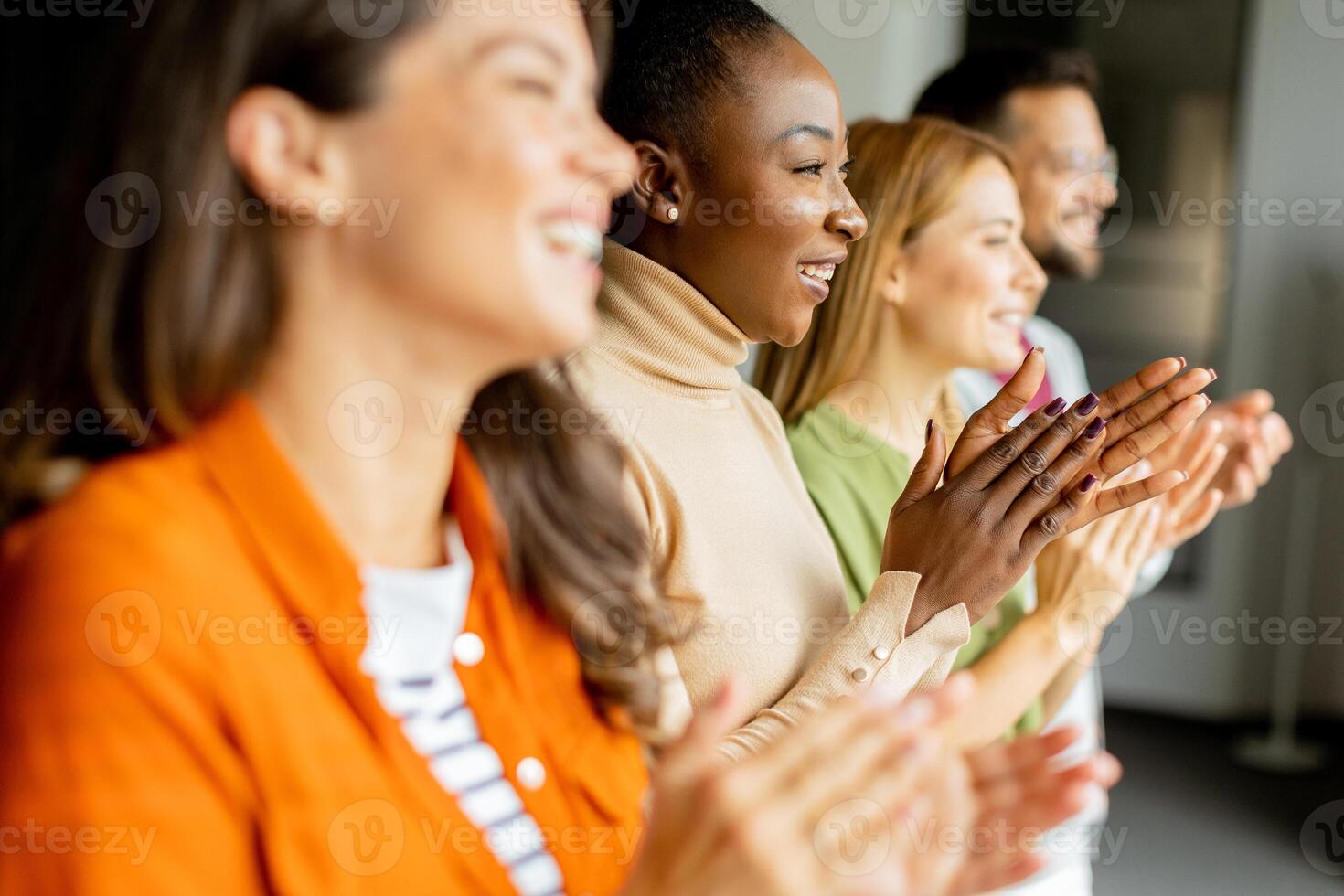 Young multiethnic startup team standing and applauding in the modern office photo