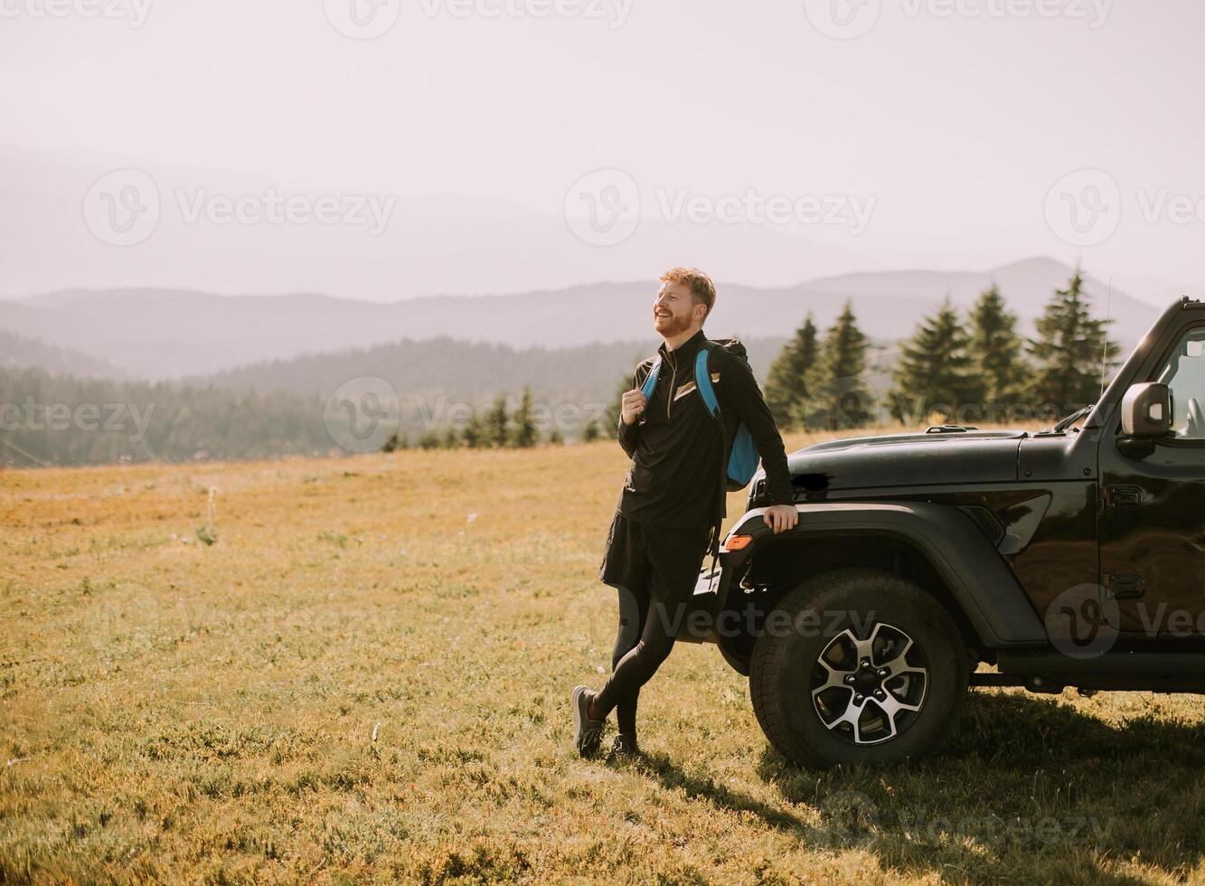 Young man relaxing by the terrain vehicle hood at countryside photo